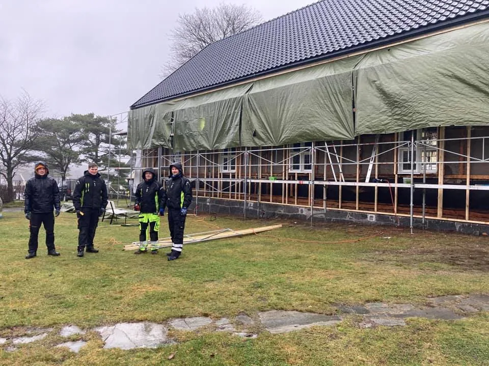 Fire tømrere fra Botnebygg foran Hvasser kirke under arbeidet med ny kledning